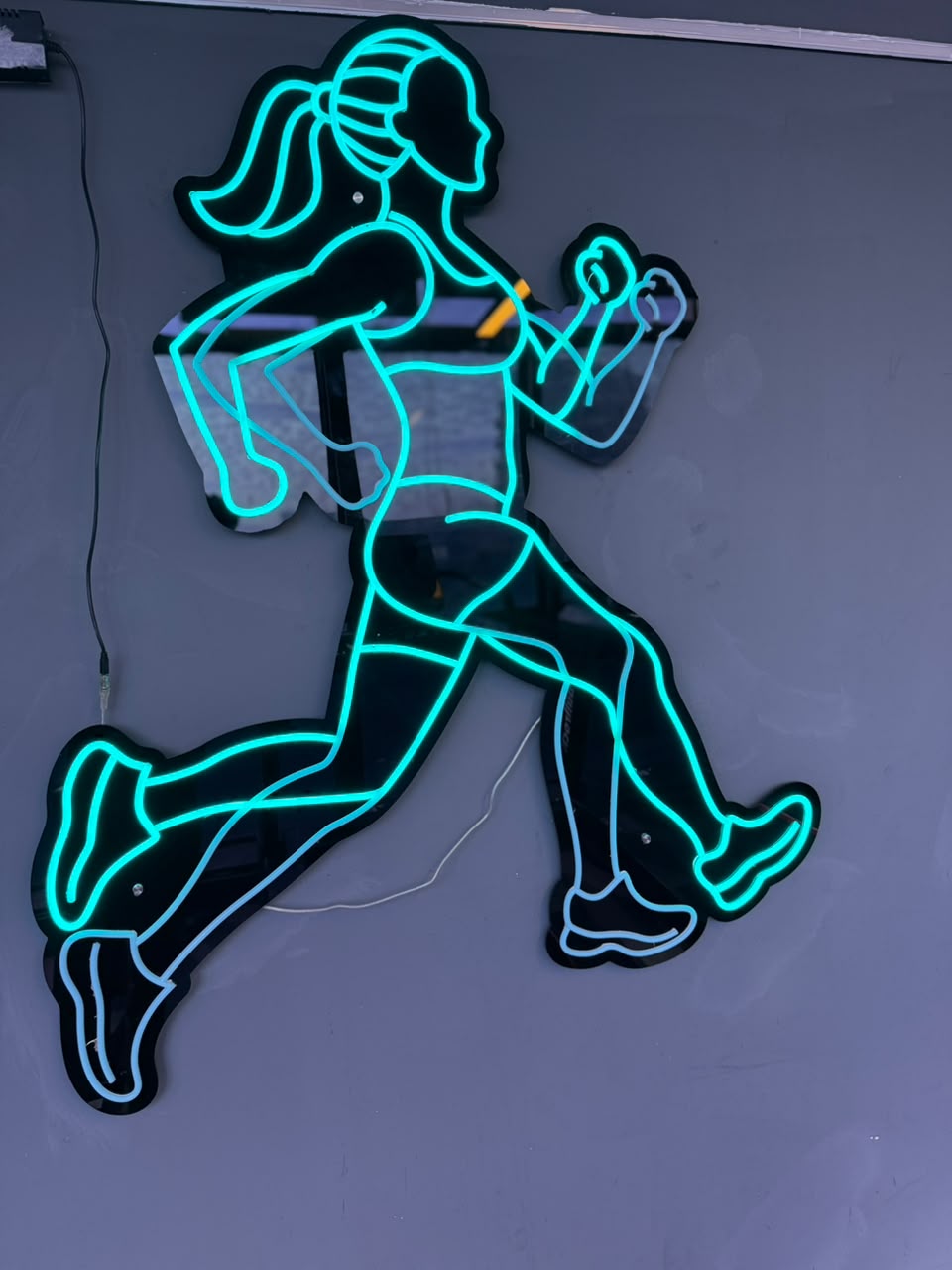 Neon runner sign on the gym wall