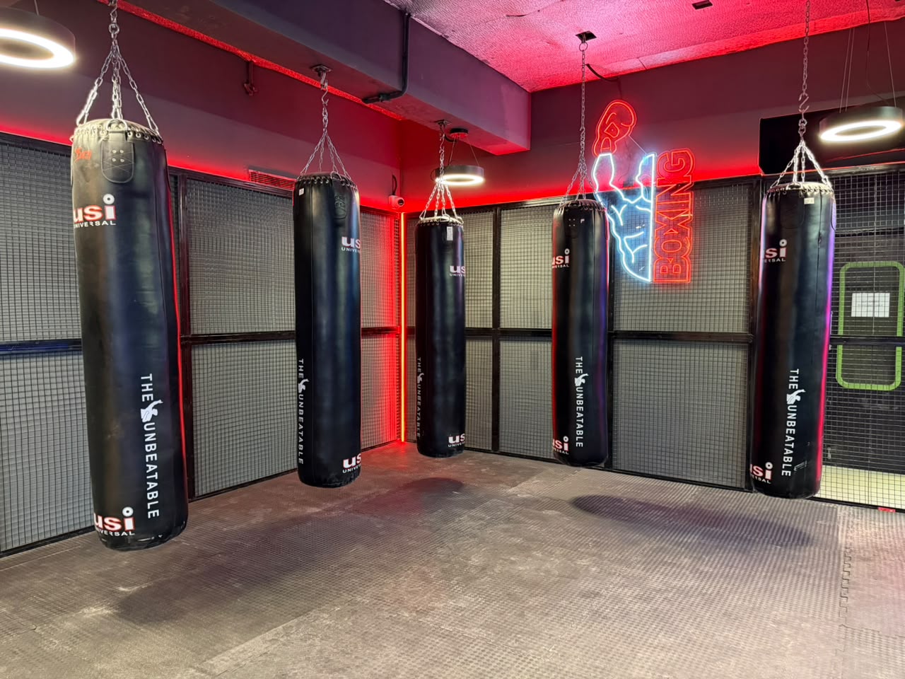 Boxing zone with heavy bags and neon signage