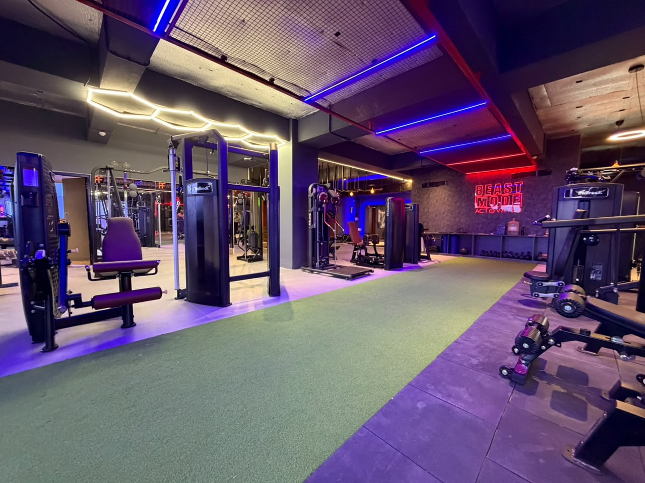 Wide training floor with BEAST MODE neon sign and hexagonal lighting